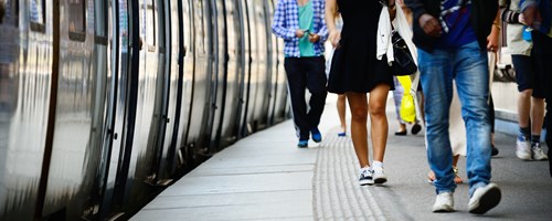 people walking on station platform with train pulled up
