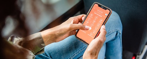 The image shows a person on board a bus using a smartphone application.